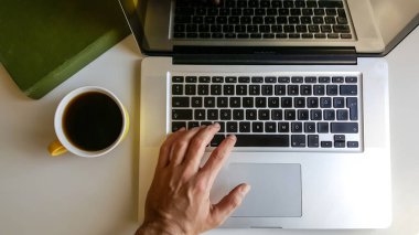 Ofis masasında bir fincan kahve ve dizüstü bilgisayar 