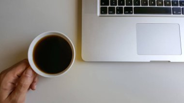 Ofis masasında bir fincan kahve ve dizüstü bilgisayar 