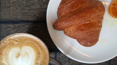 Tahta zeminde kruvasan ve kahve