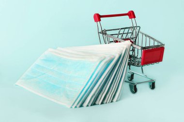 Alışveriş arabasında birkaç tıbbi maske var. Grip ve koronavirüsten korunmak için mavi maskeler..