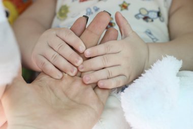 Bebek arabasında yatan küçük bir çocuk annesini parmağından tutuyor..
