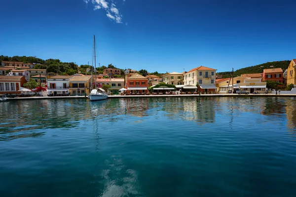 Paxos Island, Griekenland. Uitzicht op prachtige Loggos Haven baai met rustig turquoise water, schepen en jachten kleurrijke oude huizen en blauwe lucht met witte wolken. Zomer stadsgezicht. — Stockfoto