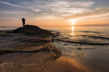 Güneş doğarken deniz manzarası. Güzel doğal deniz manzarası. Karadeniz kıyısında deniz doğuyor. Aralık ayının ortasında bulutlar ve ateş güneşiyle muhteşem bir gün doğumu. Ravda, Bulgaristan