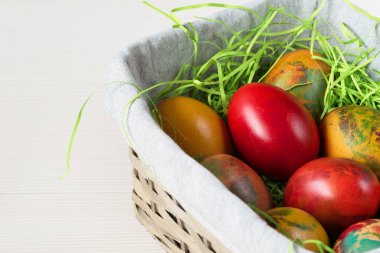 Beyaz tahta üzerinde renkli yumurtalar olan Paskalya hasır sepeti..