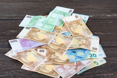 Gri ahşap tahtada para yığını.