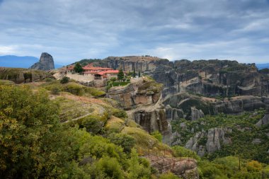 Manastır Kutsal Üçleme, Meteora, Yunanistan. UNESCO Dünya Mirası Sitesi. Uçurumun kenarında, dramatik gökyüzü arka planında tapınağı olan destansı bir manzara..