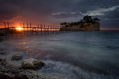Fırtınadan hemen önce güzel bir gün doğumu. Ünlü Cameo adası. Tahta köprüsü ve turkuaz suyu olan güzel küçük bir ada. Zakynthos, Yunanistan.