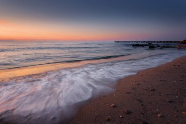 Güneş doğarken deniz manzarası. Güzel doğal deniz manzarası, mavi saat. Bulgaristan 'ın Varna kenti yakınlarındaki bir Karadeniz kıyısında deniz doğuyor. Nisan ortasında bulutlarla muhteşem bir gün doğumu..