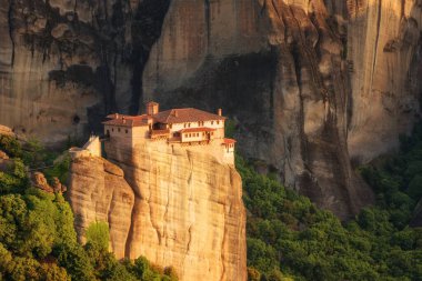 Muhteşem bahar manzarası. Rousanou Ortodoks Manastırı (St. Barbara), muazzam monolitik sütun, Meteora, Pindos Dağları, Thessaly, Yunanistan 'daki taş duvarın arka planında yeşil yapraklar..