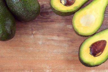 Taze kesilmiş avokadoların yakın plan fotoğrafı kahverengi ahşap arka planda görünür kahverengi tohumlar. Vejetaryen gıda konsepti, klasik tarzı, avokado arka planı..