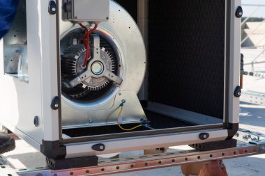 Klima üniteleri VRV (HVAC), büyük bir vantilatör ve yeni sanayi binasının çatısında mavi gökyüzü ve arka planında bulutlar olan bir soğutucu.