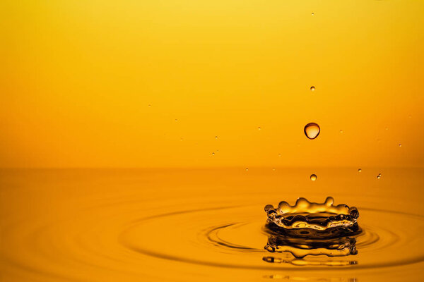 Golden Oil Drops on Yellow Background. 