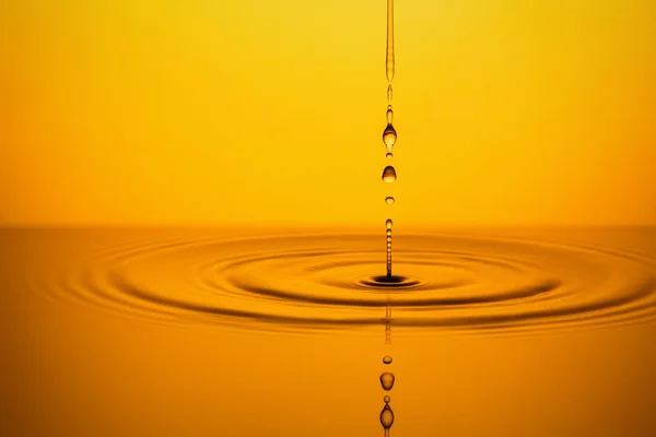 Gotas de aceite dorado sobre fondo amarillo . —  Fotos de Stock