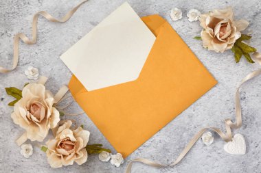 Düğün davetiyesi kağıtları güllerle süslenmiş olarak masanın üzerinde duruyordu.