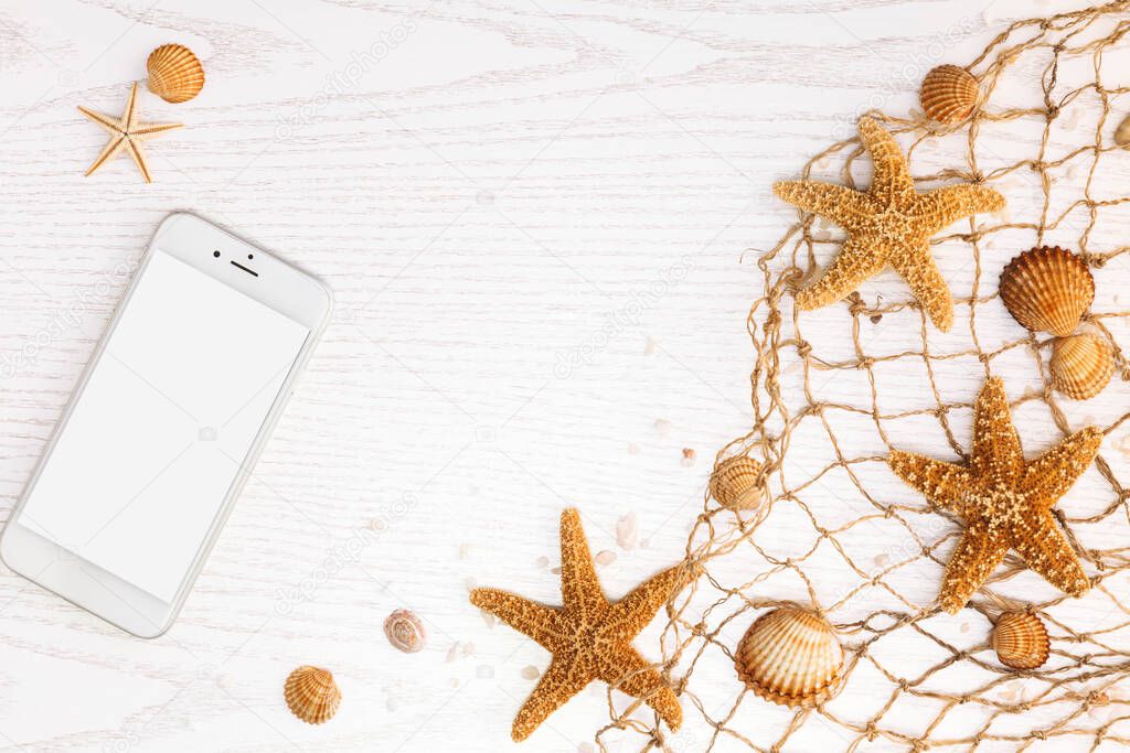 Summer time concept with sea shells and starfish on a white wooden background.