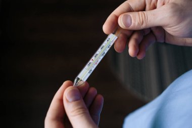 Adam ateşini ölçüyor. Doktor termometreyi tut..