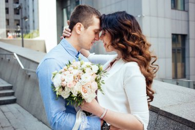 Aşk hikayesi. Yeni evliler kapalı gözlerle sarılırlar. Düğün buketi olan gelin. Güzel uzun kıvırcık saçlı gelin. Mutluluk. İlişki. Gerçek aşk. Yaşam tarzı. Yeni evlendi..