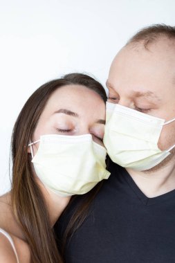 Erkek arkadaşı sarı koruyucu maskeli kız arkadaşıyla duruyor. Yakın plan portre. Beyaz arka plan. 2020 pandemik koronavirüs. Karantinaya alın. Virüs konsepti. Salgın hastalık. 