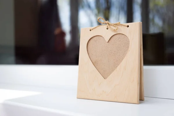 A heart-shaped photo frame stands on the windowsill