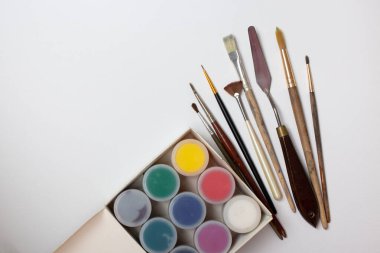 Kutuda akrilik boya, beyaz tuvalde fırçalar ve palet bıçağı.. 