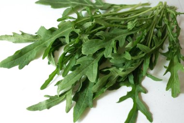 Beyaz arka planda bir demet taze roka. Baharatlı sebzeler masada. Sağlıklı vejetaryen yemekleri. Salata için bir malzeme..