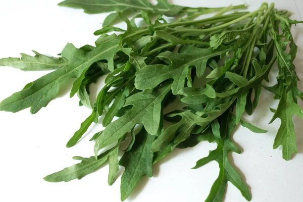 Beyaz arka planda bir demet taze roka. Baharatlı sebzeler masada. Sağlıklı vejetaryen yemekleri. Salata için bir malzeme..