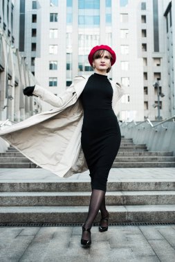 Kırmızı bereli, kırmızı dudaklı, pelerinli, siyah elbiseli, şehrin iş merkezinin yanındaki merdivenlerde yürüyen zarif bir kız. Bahar günü güzel bir iş kadını figürü. Yaşam biçimi. 