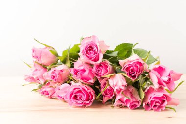 Taze, narin pembe güller ve güneşli bir yaz gününde vazoda bulanık yeşil yapraklar. Yumuşak odak ile çekilen güzel kapalı çiçek arkaplanı.