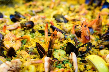 Geleneksel İspanyol paella yemeğinin büyük bir kısmını kapatıyoruz. Bir sokak yemeği festivalinde deniz ürünleri, yan görüş ve seçici bir odak noktasında deniz ürünleri ve makarna ile kızartılıyor.