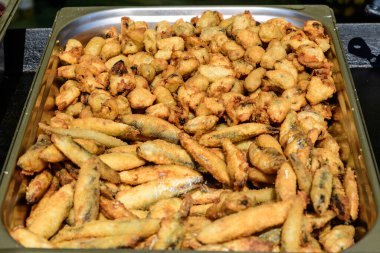 Büyük bir grup taze kızarmış kalamar ve soğan halkaları bir sokak yemeği festivalinde satışta, sağlıklı deniz ürünleri yemeye hazır, güzel turuncu tek renkli arka plan.