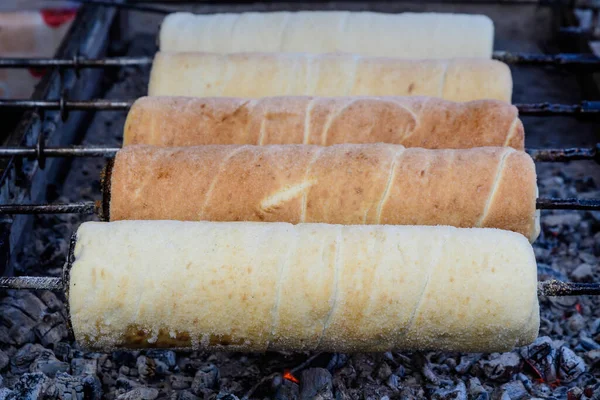 Beş taze Kurtos kalacs (Baca keki), yerel bir Macar pazarında, yumuşak odaklı geleneksel yemeklerin fotoğraflandığı ve satılığa çıkarıldığı rulo üzerinde şekerle pişirilip parlatılıyor.