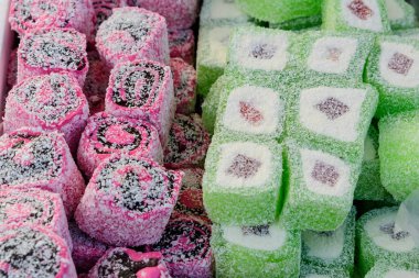 Antep fıstığı ve balla tatlandırılmış karışık Türk lokumu yığını, sokak yemekleri pazarındaki bir masada sergileniyor, geleneksel yemekler hafif odaklı çekiliyor.