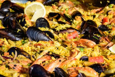 Geleneksel İspanyol paella yemeğinin büyük bir kısmını kapatıyoruz. Bir sokak yemeği festivalinde deniz ürünleri, yan görüş ve seçici bir odak noktasında deniz ürünleri ve pilav ile kızartılıyor.