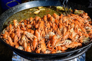 Bir sokak yemeği festivalinde büyük bir tavada domates soslu büyük porsiyon pişmiş karides ve sarı limon, sağlıklı deniz ürünleri yemeye hazır, güzel turuncu tek renkli arka plan.