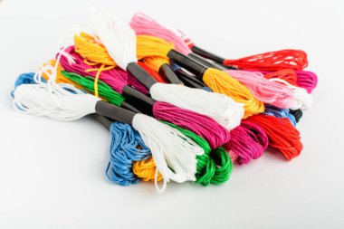 Birçok karışık renkli dikiş iplikleri beyaz bir masa üzerinde nakış için, yan görünüm kırmızı, pembe, sarı, mavi, siyah ve yeşil tekstil materyalleri