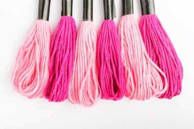 Beyaz bir masa, üst görünüm veya düz döşeme tekstil materyalleri kapalı nakış işleme için birçok karışık pembe dikiş iplikleri