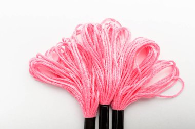 Beyaz bir masa, üst görünüm veya düz döşeme tekstil materyalleri üzerine nakış işlemek için üç canlı pembe dikiş ipliği