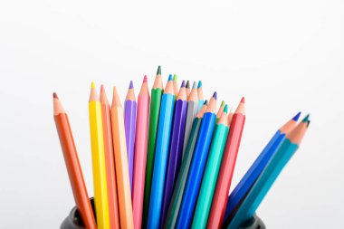 Beyaz bir masa üzerinde izole edilmiş bir siyah kutuda bir sürü karışık renkli kalem grubu, çocuk okulu veya ofis tedarikçileri yan görünüşten yumuşak bir odak ile fotoğraflanmış, metin için boşluk ile