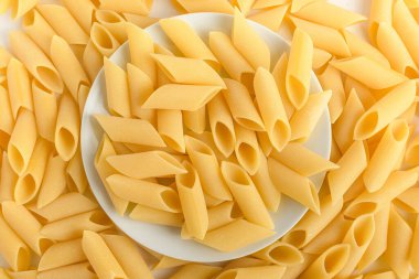 Kurutulmuş meze makarna yığını pişirilmeye hazır İtalyan makarnası, beyaz bir masada izole edilmiş, üst ya da düz sağlıklı yiyecekler. 