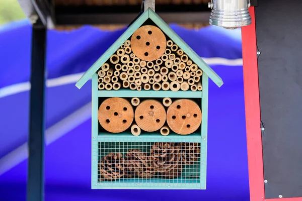 Hand made wooden bug hotel for attracting pollinators in a garden, displayed for sale at a street market, photographed with soft focus