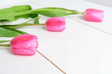 Pek çok küçük, canlı sarı gül çiçekleri ve yeşil yapraklar ham ahşap bir masa üzerinde, güzel kapalı çiçek arka planı küçük odak ile fotoğraflanmış