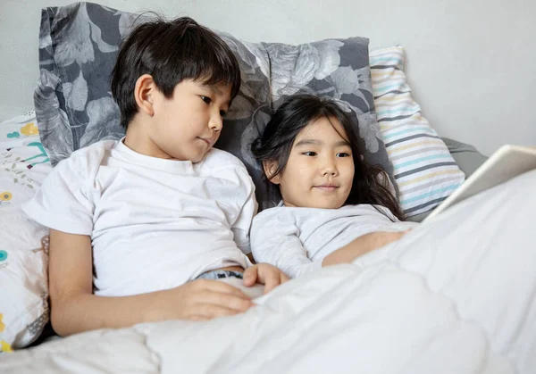 Çocuklar yatakta kitap okuyor.