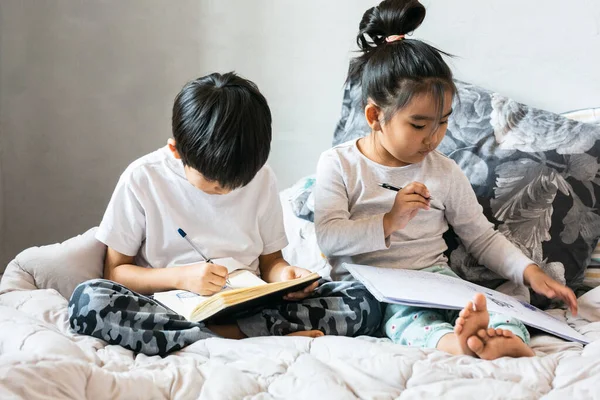 Çocuklar yatakta kitap okuyor.