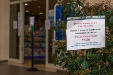 Florence, Toskana, İtalya - 03 / 20 / 2020: Coronavirus salgını, COVID-19 salgını, bir eczanenin önünde asılı uyarı işareti müşterileri kurallara uymaya davet ediyor