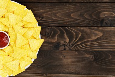 Tahta zemin üzerinde sos olan bir tabakta Meksika mısır cipsi. Boşluğu kopyala.