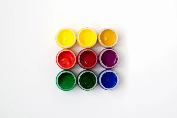 Guache in banks on a white background. Nine bright colors.