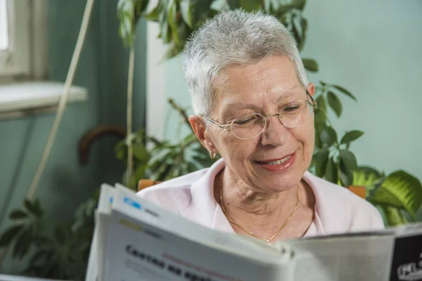 Бабушка читает газетные статьи — стоковое фото
