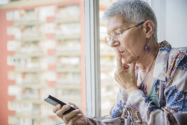 Oude dame verward met haar mobiele telefoon — Stockfoto