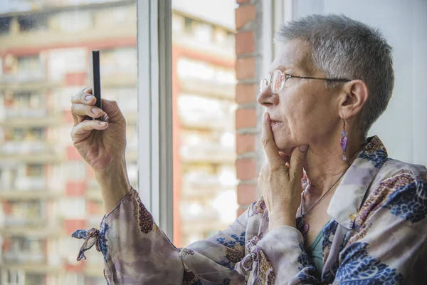 Velha senhora confundida com seu telefone celular — Fotografia de Stock