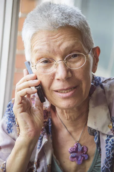 Mujer mayor teniendo una charla amistosa en su teléfono celular — Foto de Stock